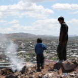 Two boys stand on top of what is left of makeshift homes destroyed by a fire. Most of the families lived by the dump in Nogales, Sonora, where they scavenge for plastic, cardboard and aluminum to sell to private recycling companies.
